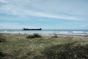 A large boat where fish are stored standing firmly near the beach