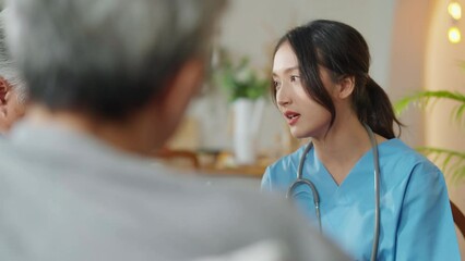 happiness Cheerful elderly woman and men talking with female caregiver nurse doctor having health checking consult at living area,Caretakers with senior couple sitting in living room at nursing home 