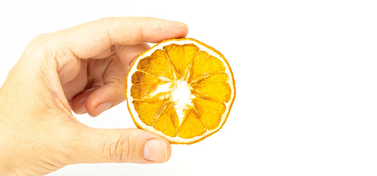 Dried Orange Slice Isolated On White Background. Hand Holding A Slice Of Citrus Fruit. Selective Focus.