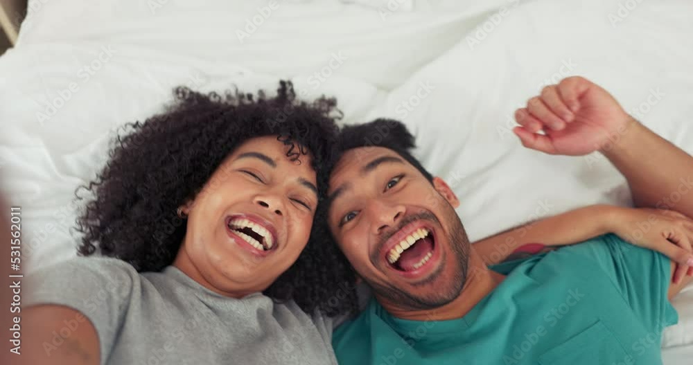 Poster Happy fun couple, selfie and bed in playful relationship laughing together in happiness at home. Interracial man and woman smile, love and live stream joyful funny moments lying in the bedroom