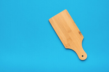 Wooden cutting board on a light blue background. Flat lay.