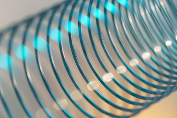 Closeup of coiled metal spring with sufficiently high strength and elastic properties in neon blue...