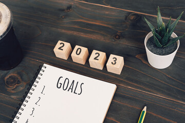 2023 goals text on notepad with coffee cup and pen on wooden desk