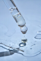 Dropper with serum or cosmetic oil on a blue background.