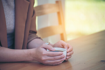 Close up Hands of businesswoman love drinking hot coffee. Woman hand holding black coffee cup in green garden cafe. business women with black coffee or hot chocolate in coffee shop. Caffeine drinking