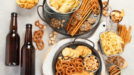 Assortment of beer and salty snacks on light background.