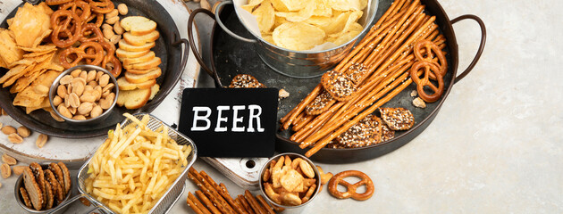 Assortment of beer and salty snacks on light background.