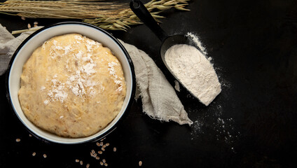 Raw dough pastry in a bowl on dark background.