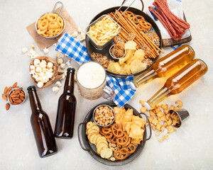 Assortment of beer and salty snacks on light background.