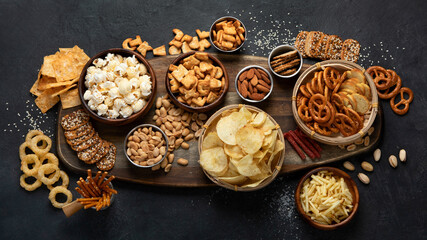 Assortment of salty snacks on dark background.