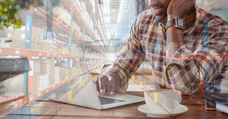Mixed race man using laptop shopping online over a warehouse full of boxes 