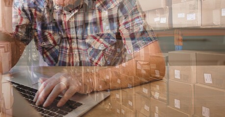 Caucasian man using laptop shopping online over a warehouse full of boxes 