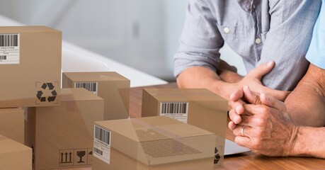 Caucasian couple using laptop shopping online with a pile of boxes 