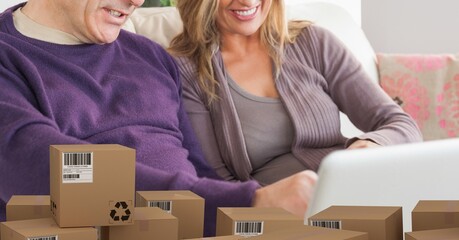 Caucasian couple using laptop shopping online over a pile of boxes