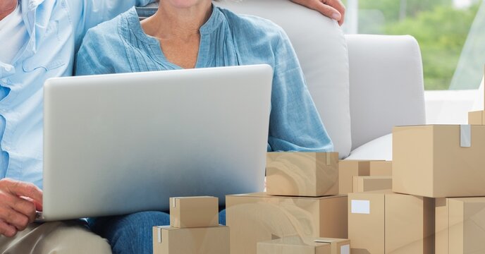 Caucasian woman using laptop shopping online with pile of boxes 
