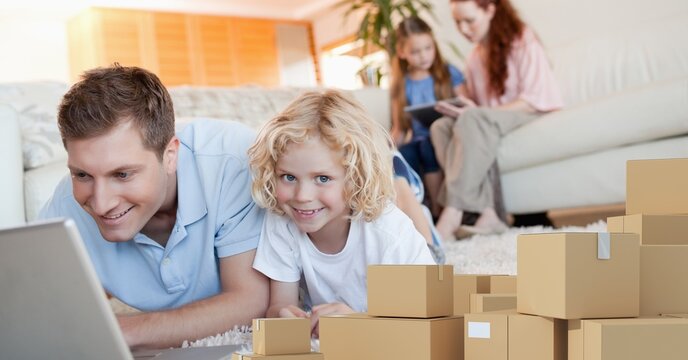 Caucasian man and his son using laptop shopping online with a pile of boxes 
