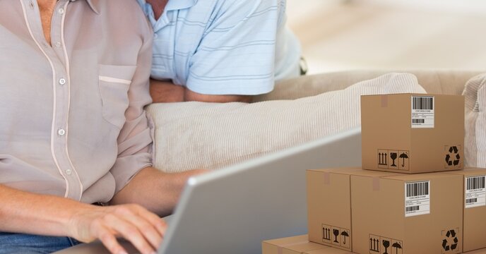 Caucasian couple using laptop shopping online with a pile of boxes 