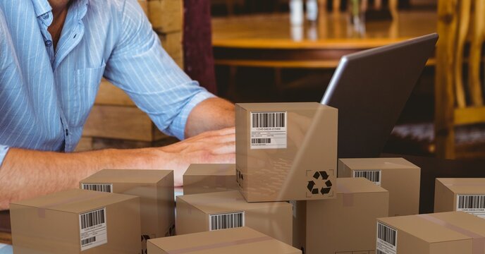 Caucasian man using laptop shopping online with a pile of boxes 