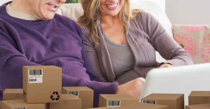 Caucasian couple using laptop shopping online over a pile of boxes