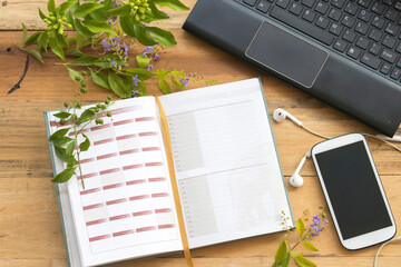 notebook planner, mobile and computer for business work arrangement flat lay style on background wooden