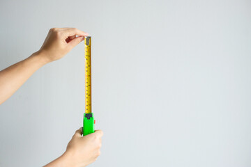 Man hand using tape measure for measuring with wall backgrounds at home. DIY, Interior design,...