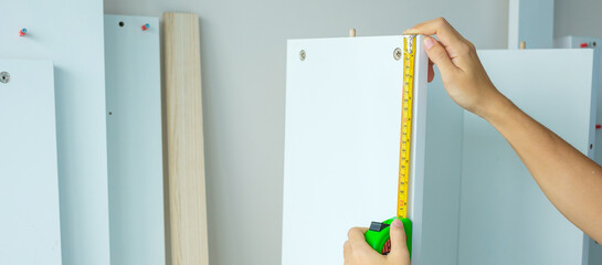 Man hand using tape measure for measuring furniture at home. DIY, Interior design, repairing and...