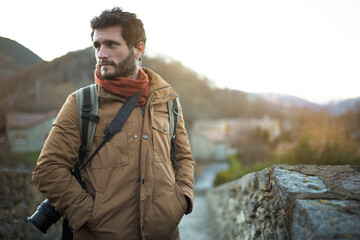 Handsome man standing outdoors in nature in winter. Male photographer going on trekking, hiking...