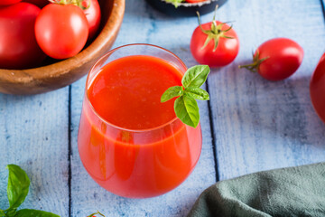 Organic homemade tomato juice with basil leaves in a glass on the table