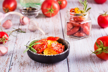 Dried tomatoes with spices and garlic in a bowl and fresh vegetables on the table. Homemade snack
