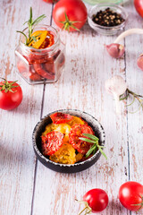 Sun-dried tomatoes with spices and herbs in a bowl and fresh vegetables on the table. Vertical view
