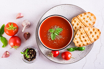 Fresh tomato soup with basil in a bowl and fresh vegetables on the table. Top view
