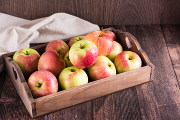 Wooden box with fresh ripe apples on a wooden table. Local seasonal fruits.