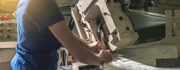 Woman in the process of sewing on professional equipment. Sewing fabric in production
