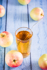 Organic homemade apple juice in a glass with a straw and fruits on the table. Vertical view