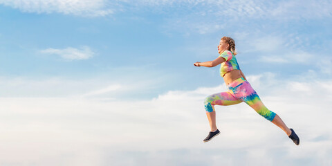 Young girl gymnast flies in long jump against background of blue summer evening sky. There is no ground under your feet.