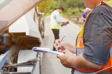 Closeup and crop insurance agent writing on clipboard while examining car after accident claim...