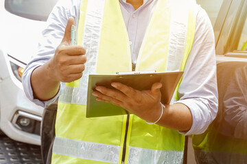 Closeup and crop Insurance agent thumbs up is a sign of great work and hold a work list clipboard with sun flare and car background.