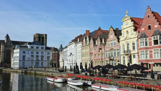 GHENT, BELGIUM - AUGUST 06, 2022: Summer streets and riverside of Ghent decorated with bloomy flowers. Buildings along River Scheldt, Flemish Region.