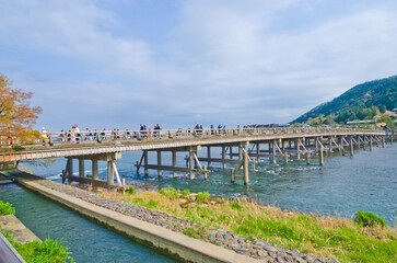 Fototapeta na wymiar People crossing the Oi River on Togetsukyo Bridge in Arashiyama, Japan.