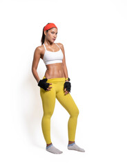 Full body length shot of young sporty Asian woman fitness model in white-top sportswear and red headband standing in a relaxed pose. Fitness and healthy lifestyle concept.