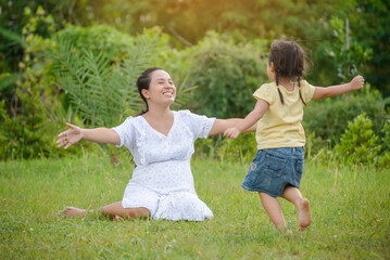 Naklejka na ściany i meble Pregnant Asian Mother and Happy daughter greeting, proud and hug together. Mom and adorable little Child playing together outdoor at rice field. Mother's day and Happy family Concept.