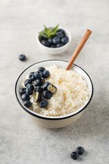 Rice milk porridge with blueberries in a bowl close-up. The concept of a healthy and tasty breakfast.