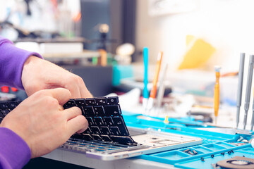 Worker technician repairing broken laptop notebook with screwdriver, keyboard replacement for modern computer