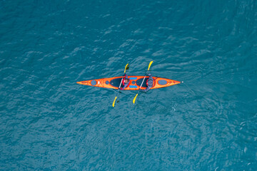 Red kayak boat two rowers on blue turquoise water sea, sunny day. Concept extreme sport, aerial top...