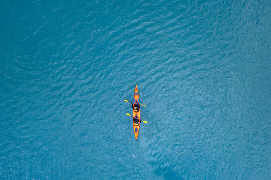 Red kayak boat two rowers on blue turquoise water sea, sunny day. Concept teamwork for business plan, aerial top view