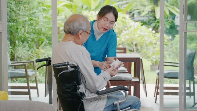 Asian young woman nurse pills with help prescribes medicine to older disabled patient on wheelchair when elderly senior man patient's time to go home at nursing home care. Medicine and health care