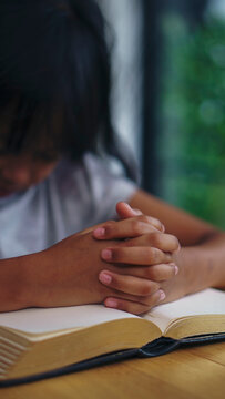 Prayer and bible concept. Asian kid praying, hope for peace and free from war and coronavirus, Hand in hand together by child. Little Girl believes and faith in christian religion at church-vertical
