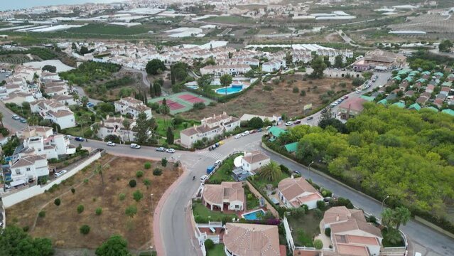 tilting up from residential housing area towards sunset over sea, and then tracking from right to left revealing more of the coastline.