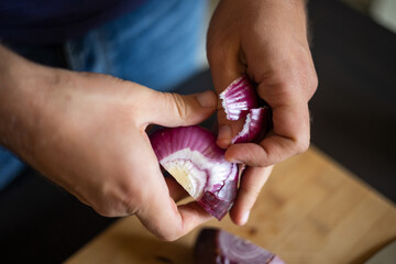 man peeling red onion close up