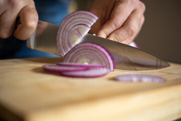 Obraz na płótnie Canvas man hands cutting red onion close up on wooden board